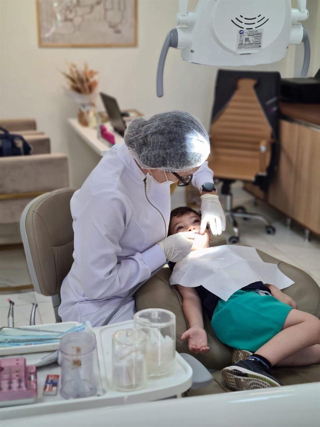 Atendimento odontológico infantil, com a criança tranquila durante o exame.